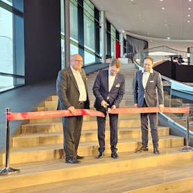 Auf dem Bild sind drei Männer zu sehen, die ein rotes Einweihungsband durchschneiden.