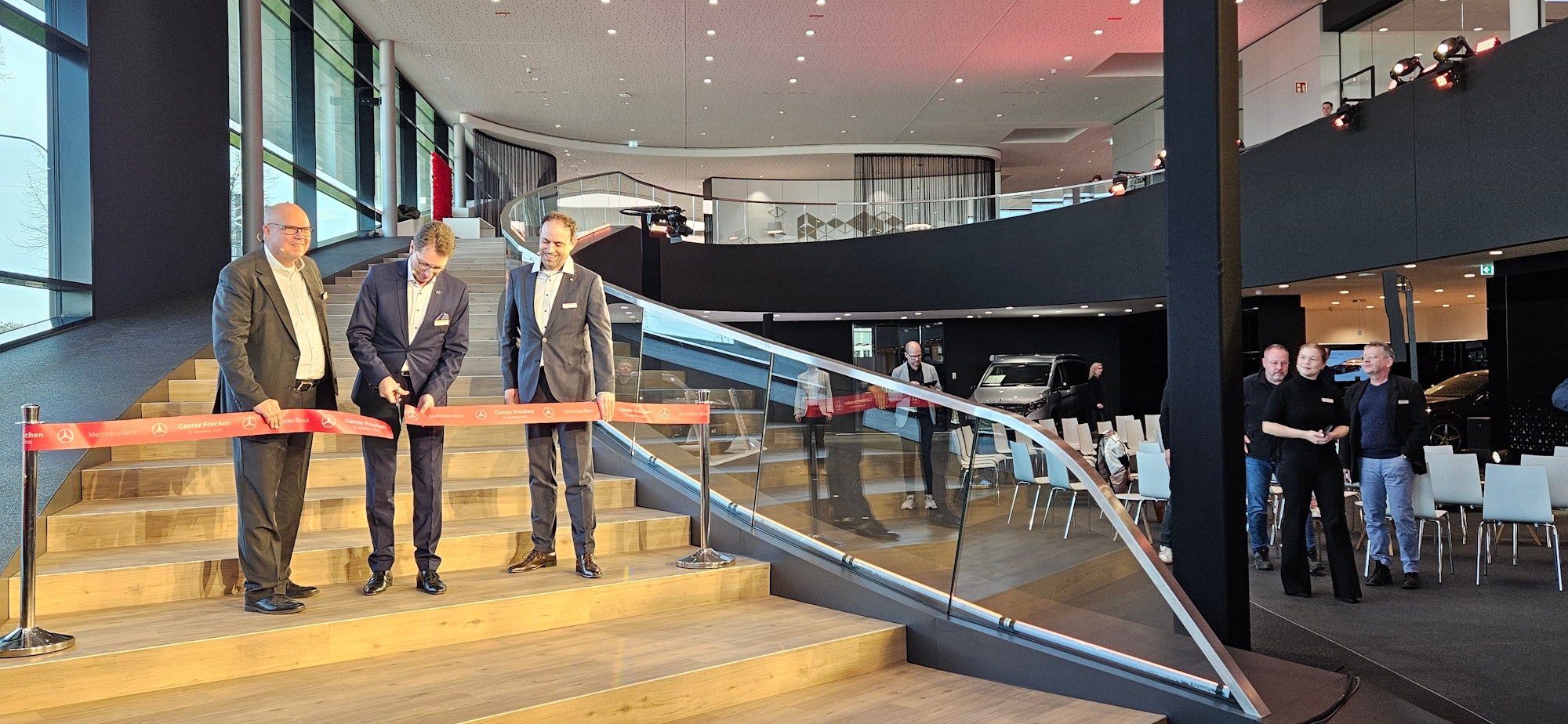 Auf dem Bild sind drei Männer zu sehen, die ein rotes Einweihungsband durchschneiden.