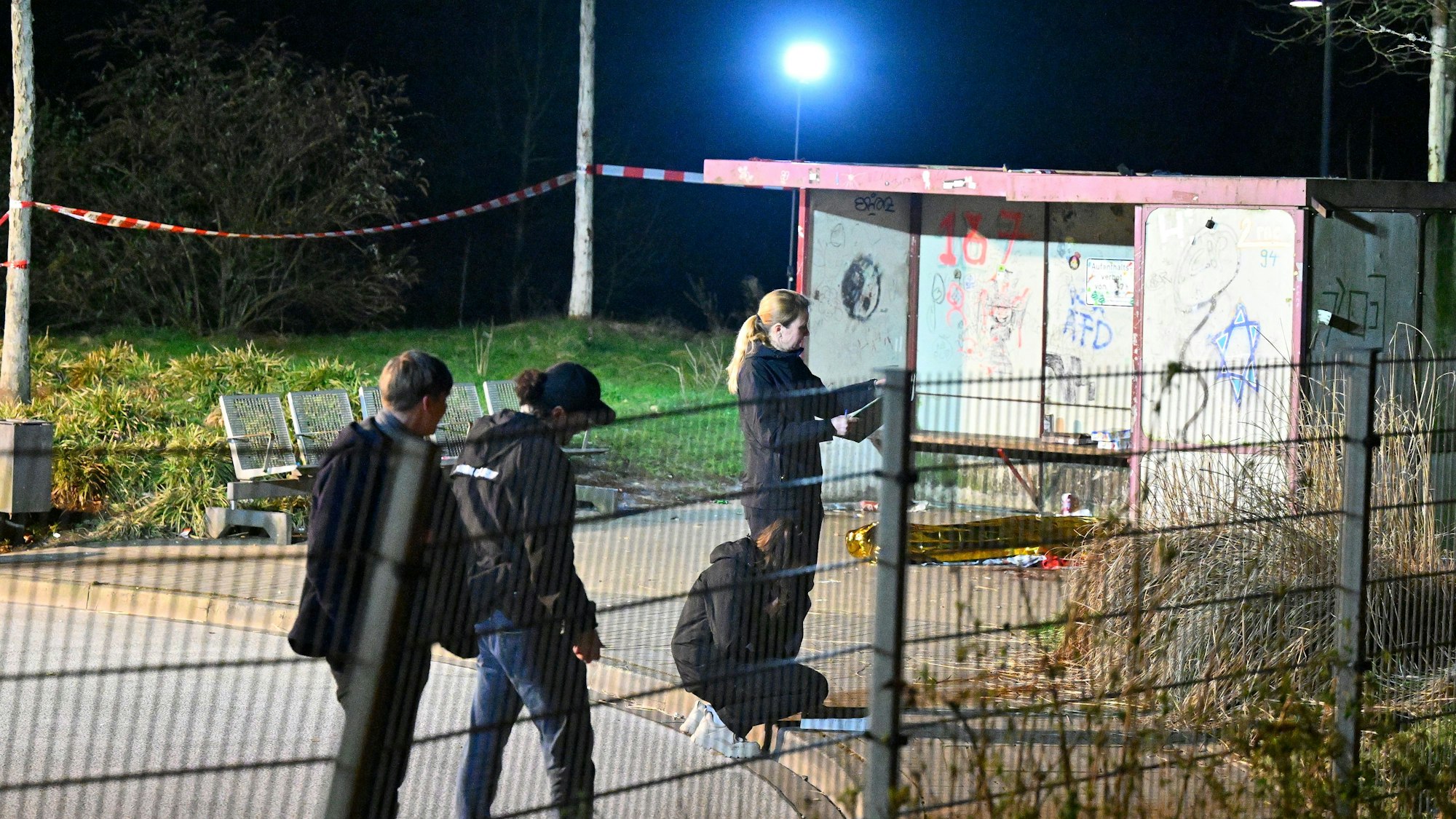 Das sogenannte Trinkerbüdchen neben dem Gummersbacher Busbahnhof. Polizisten fotografieren nach einem Mord Spuren. Im Hintergrund liegt eine mit Goldfolie abgedeckte Leiche.
