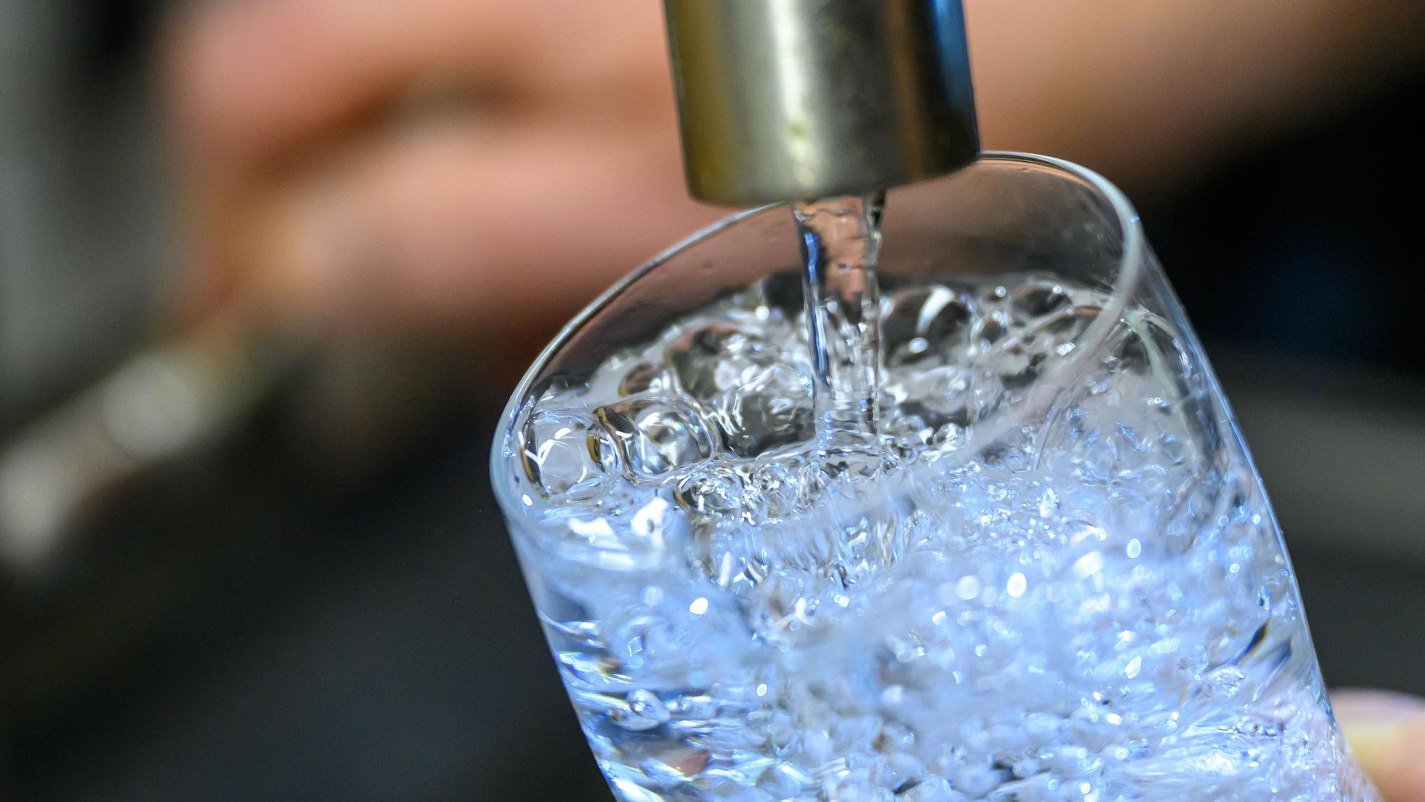 Das Symbolfoto zeigt einen Wasserhahn, aus dem Wasser in ein Glas fließt.