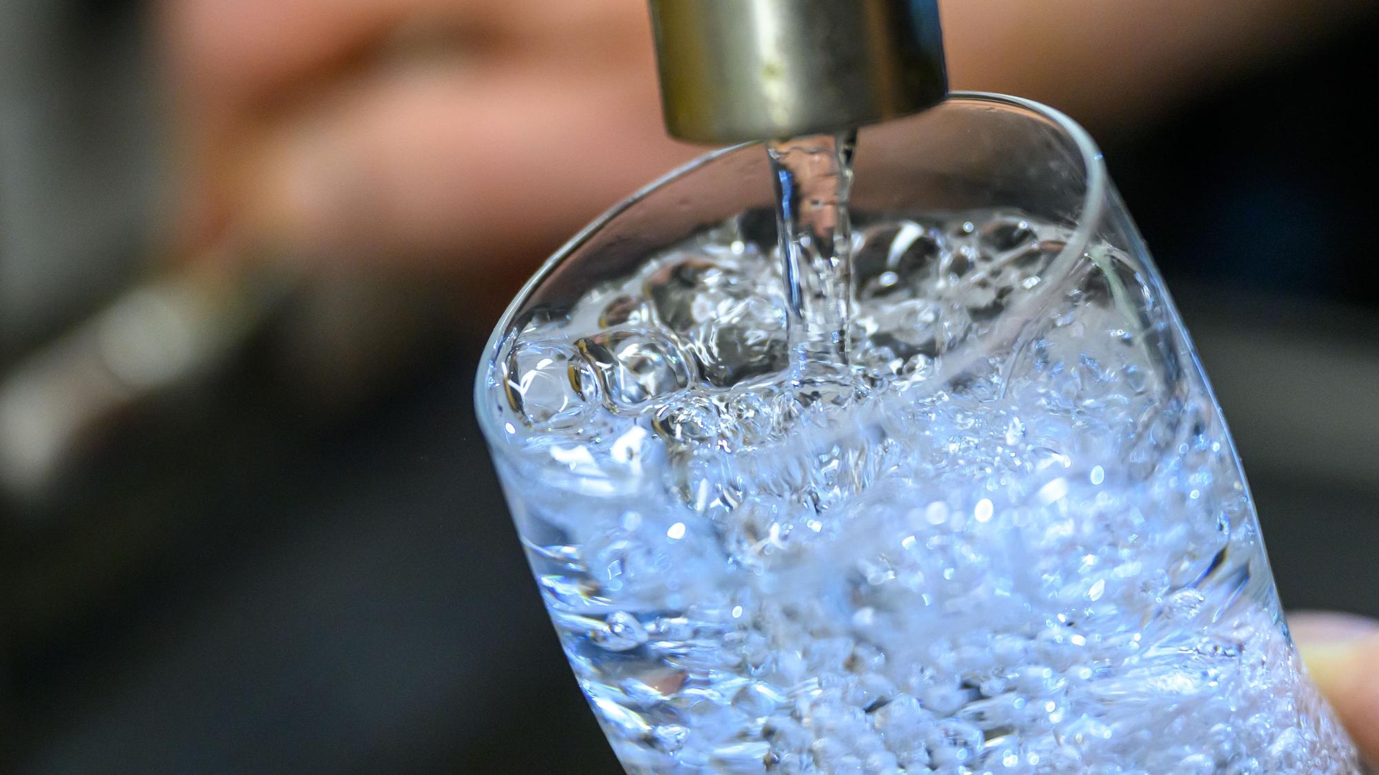 Trinkwasser läuft aus einem Wasserhahn in ein Glas.