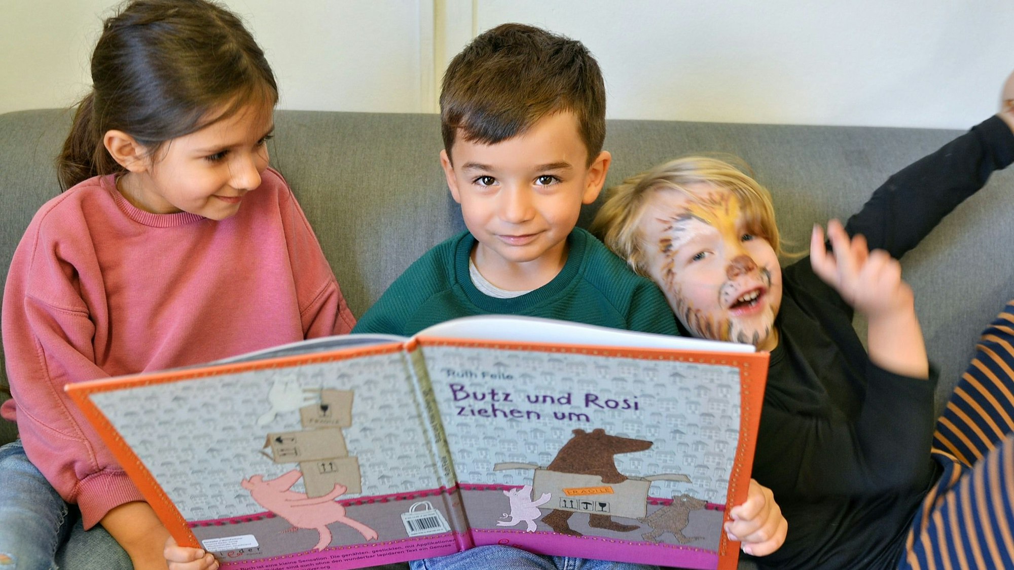 Drei Kinder schauen sich in der Kita „Wirbelwind“ ein Bilderbuch an.