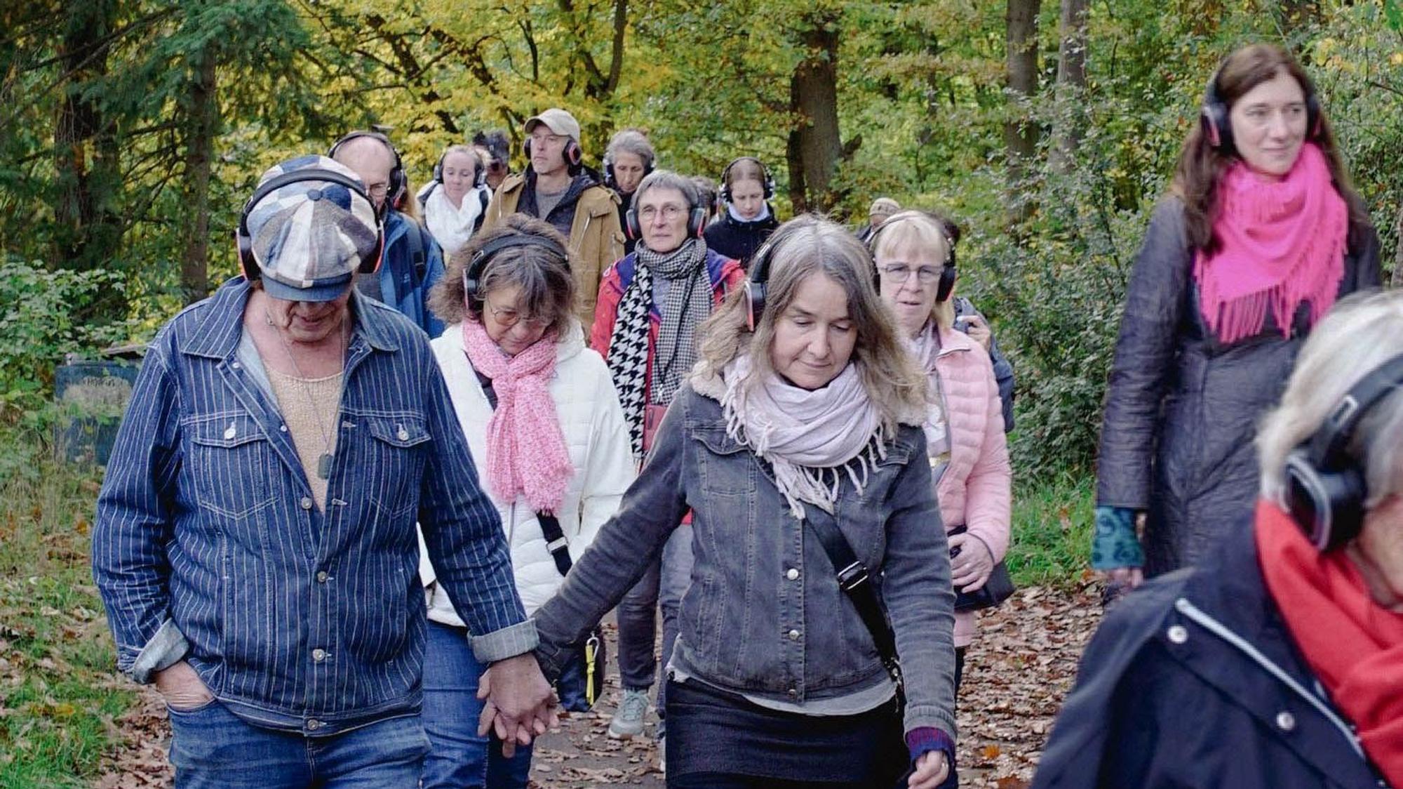 Auf einem Weg an der Steinbachtalsperre laufen Menschen, die alle einen Funkkopfhörer tragen.