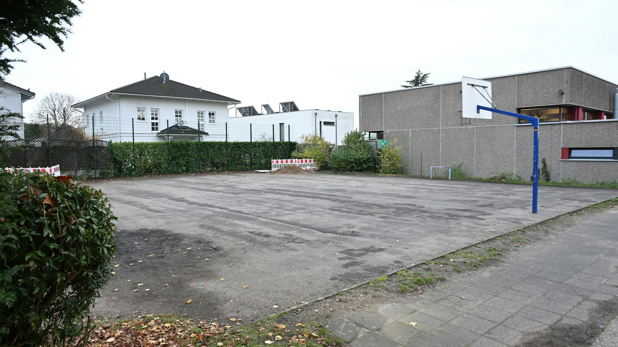 Am Rand der Asphaltfläche steht ein Basketballkorb.