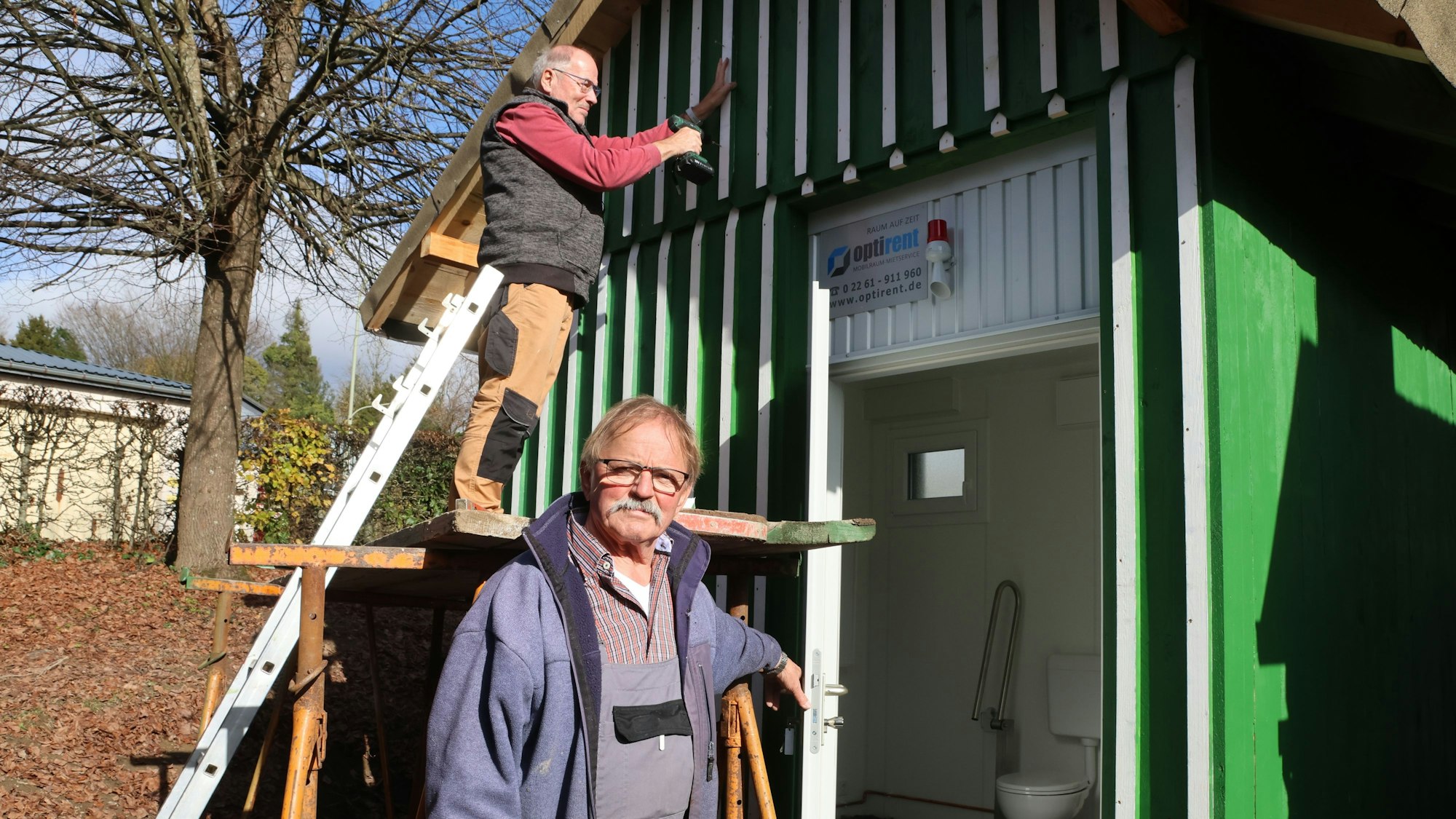 Das Foto zeigt die barrierefreie Toilette und zwei Ehrenamtler