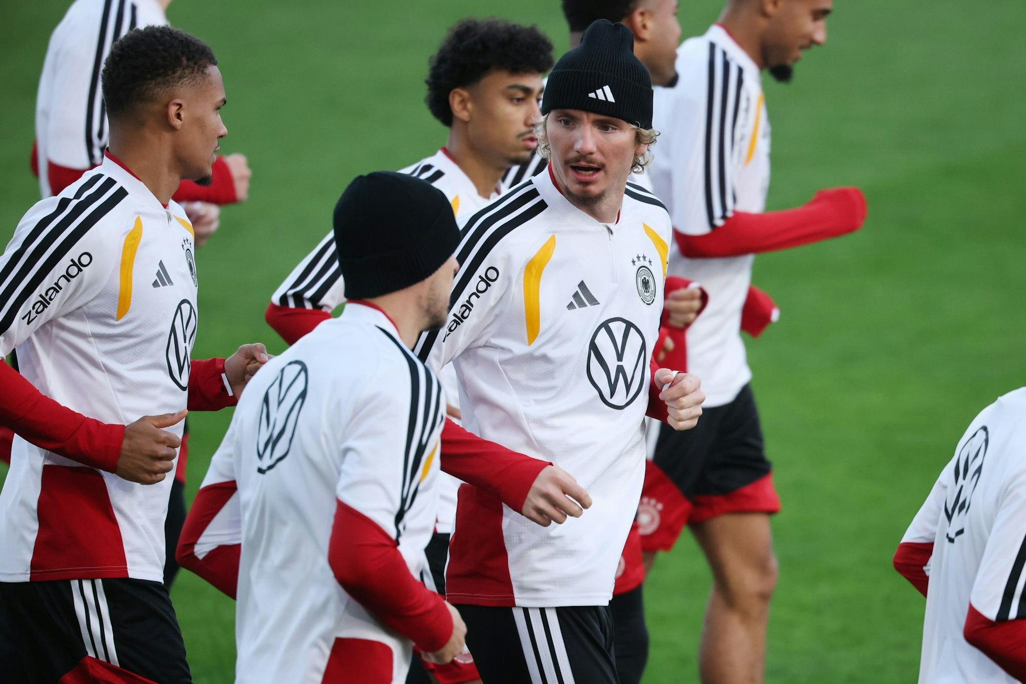 Thiaw (l.) und Woltemade (mit Mütze in der Mitte) laufen beim DFB-Training.