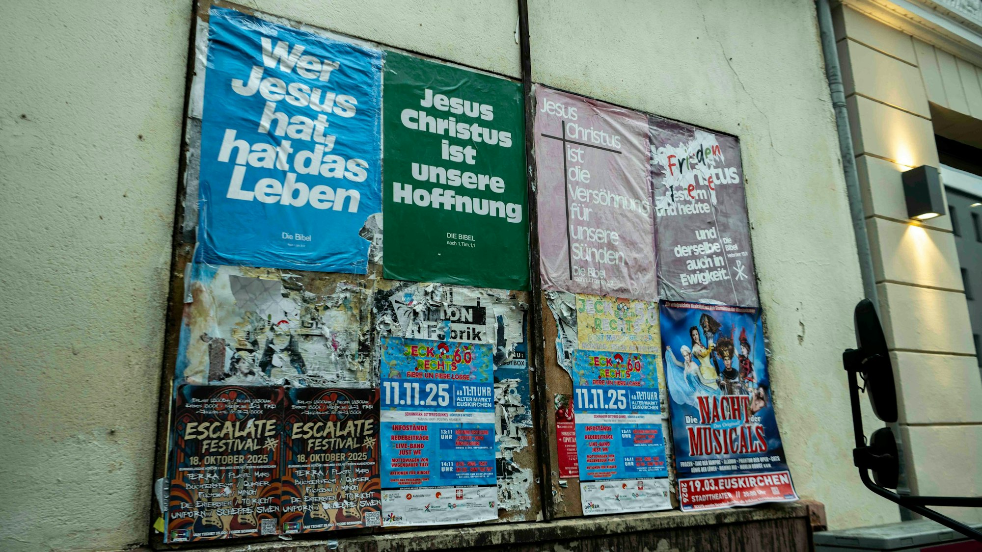 Auf einer Tafel an einer Hausfassade in Euskirchen kleben zahlreiche Werbeplakate.