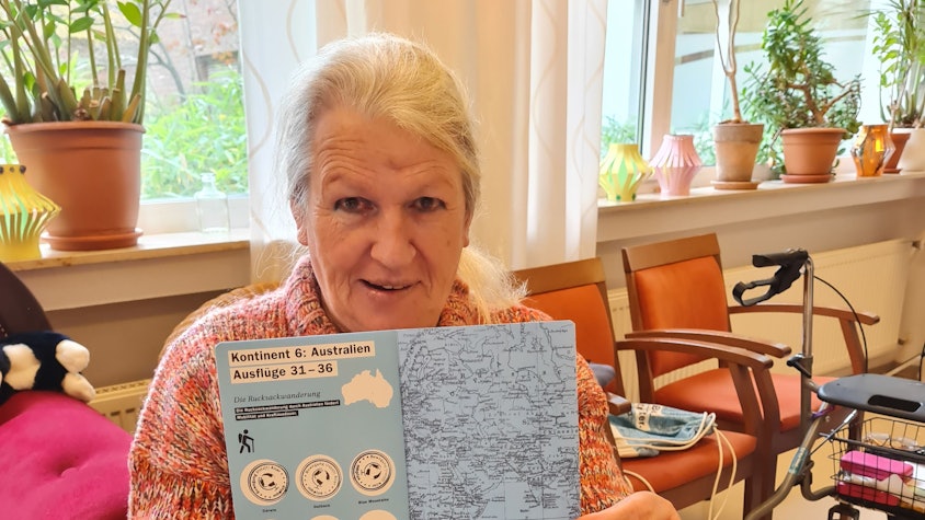 Eine Frau hält ein Heft mit Stempeln in die Kamera.