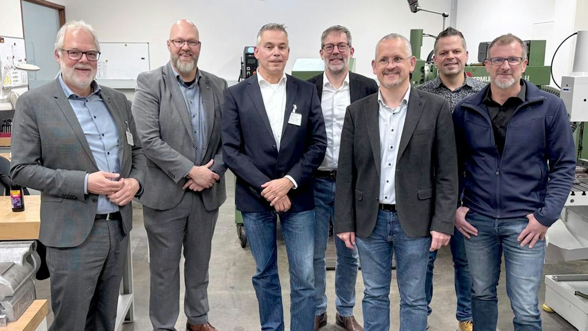 Die sieben Teilnehmer der PK (alles Männer) stehen nebeneinander.