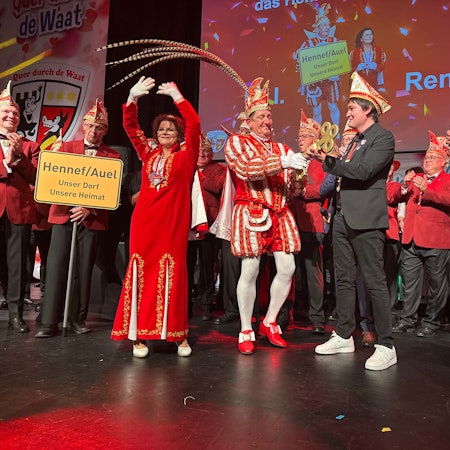 Skeptisch schaut Prinz Uli I., als ihm Bürgermeister Mario Dahm den Schlüssel fürs Rathaus bei der Prinzenproklamation 2025 in Hennef übergibt, Renate I. jubelt. Moderator Jörg Steinhauer (r.) freut sich.