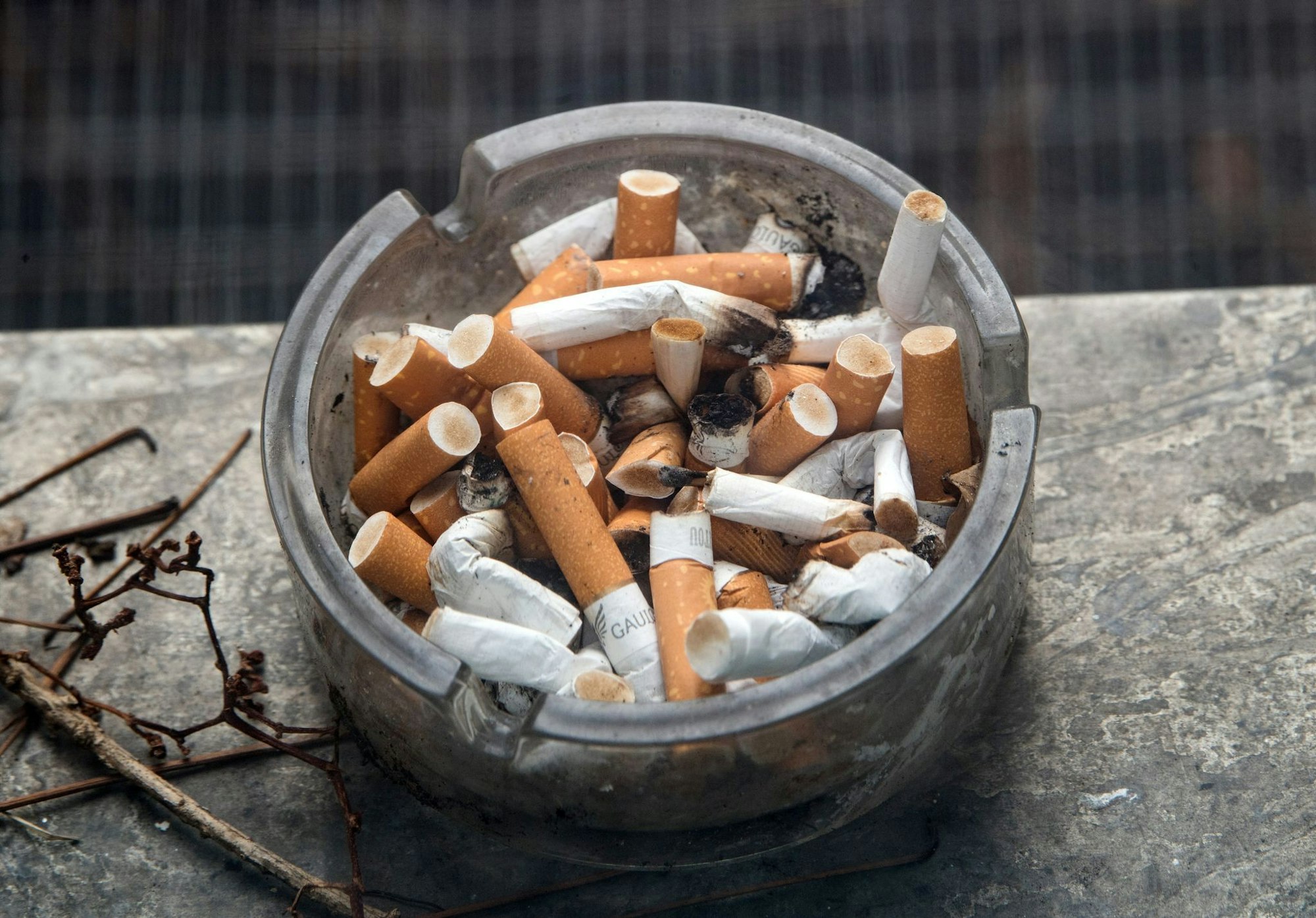 Ein voller Aschenbecher steht auf einem Fensterbrett.