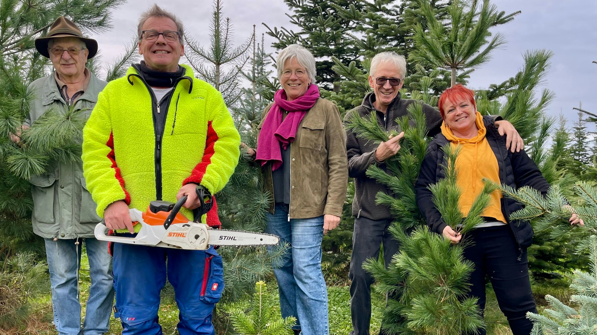 Fünf Menschen stehen inmitten von Nadelbäumen.