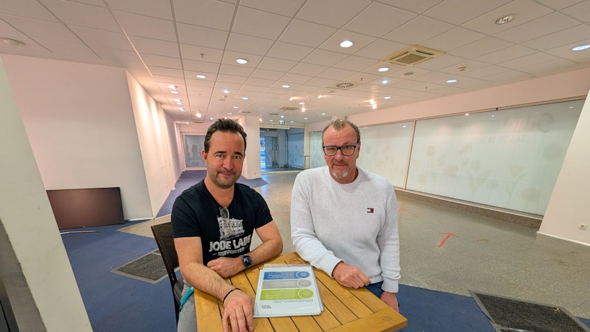 Das Foto zeigt die beiden Betreiber auf Hockern an einem Stehtisch in den Räumen der früheren Postfiliale im Hürth-Park.