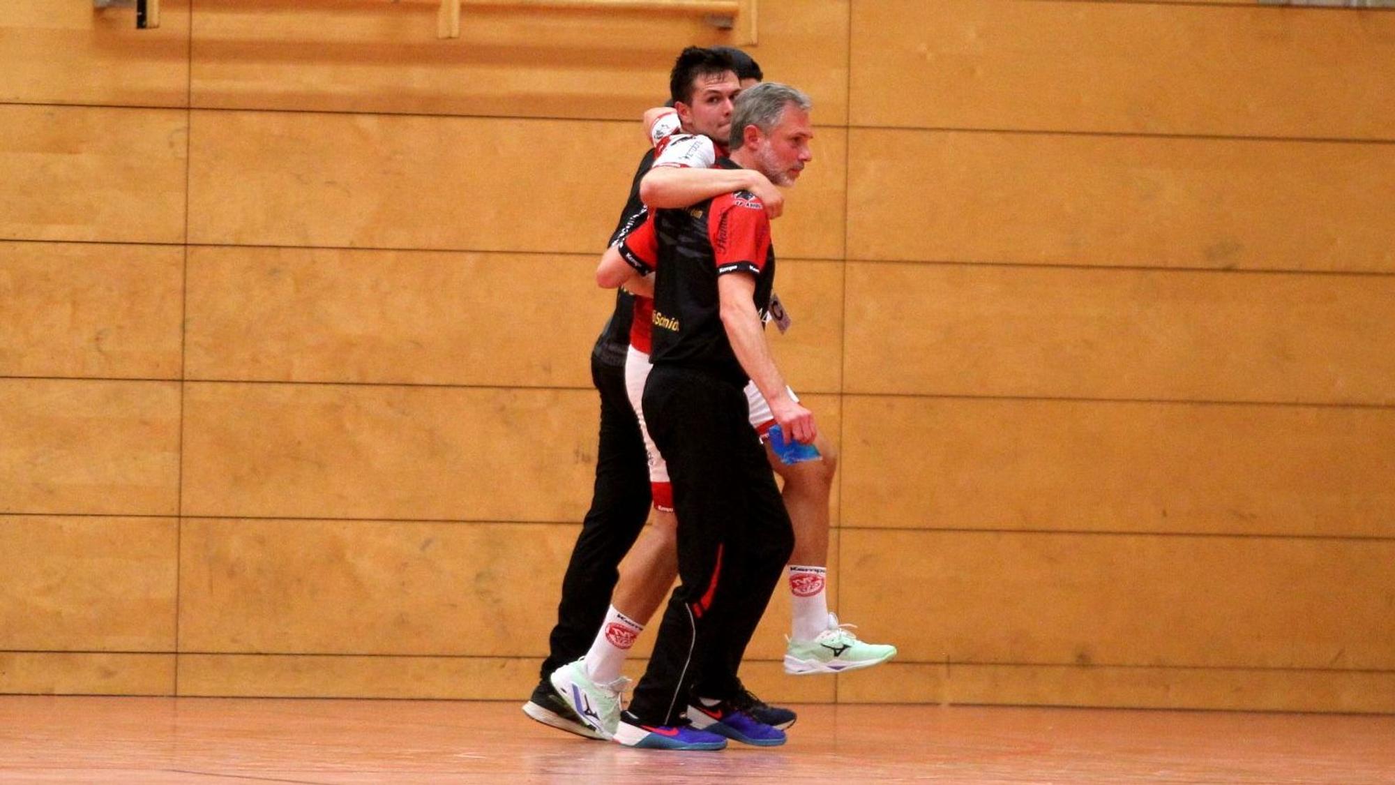 Lukas Königshoven wird von zwei Betreuern, die ihn stützen, aus der Halle begleitet.