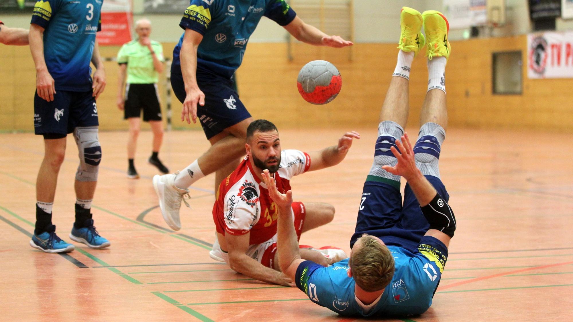 Dennis Schüller liegt halb auf dem Boden und passt, ein Gegenspieler liegt rücklings vor ihm.