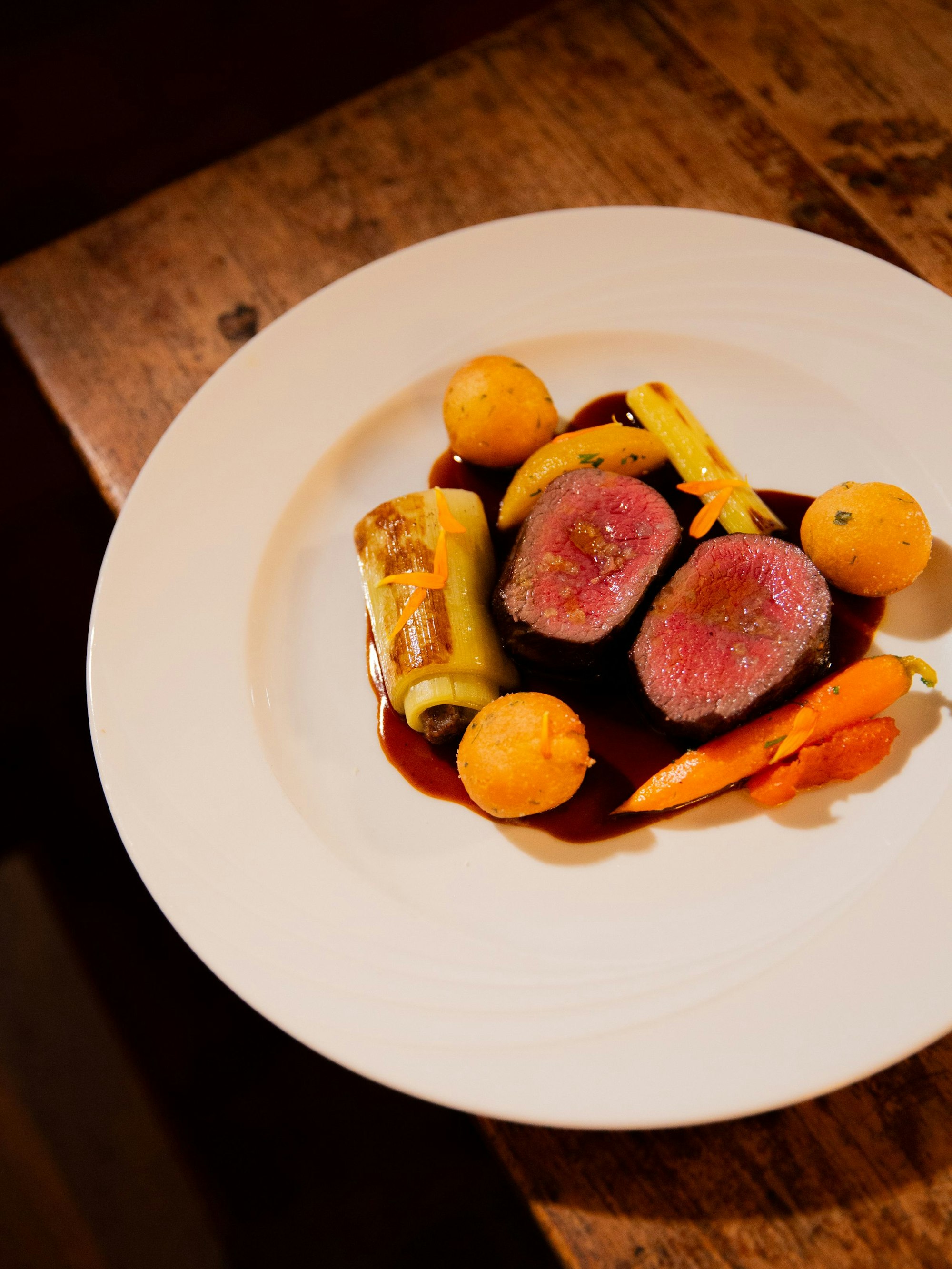 Hirschmedaillons mit gefülltem Lauch, Möhrchen und Pfirsich.