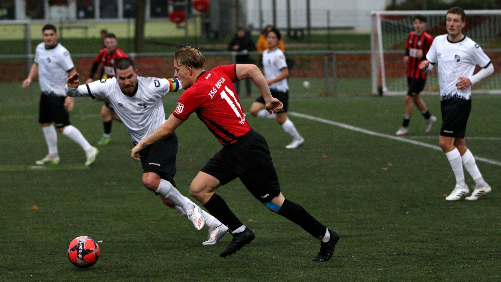 Der Spieler der JSG Erft geht mit Tempo am gegnerischen Kapitän vorbei, der böse guckt.
