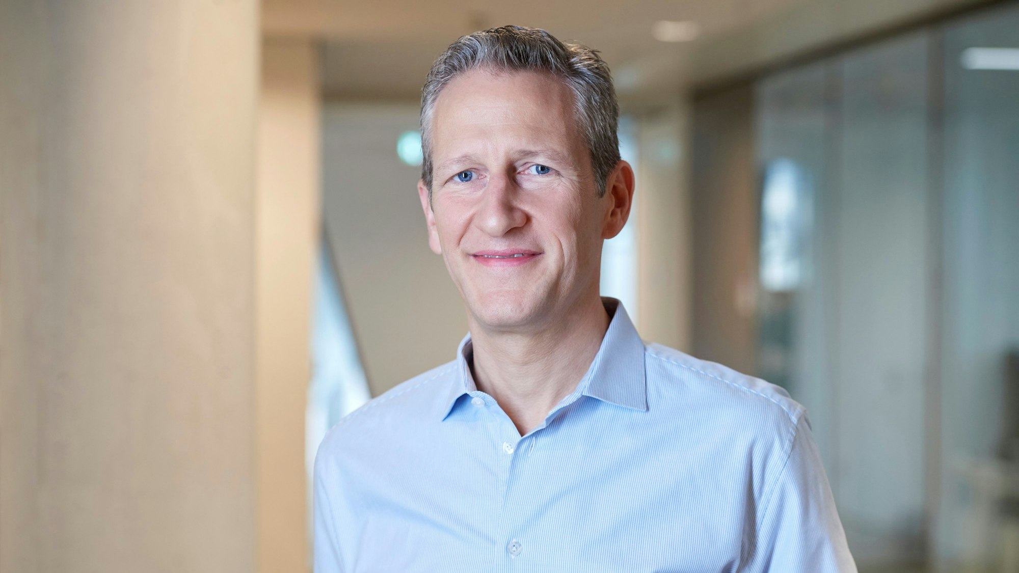 Ein Mann in Bürokleidung lächelt in die Kamera.