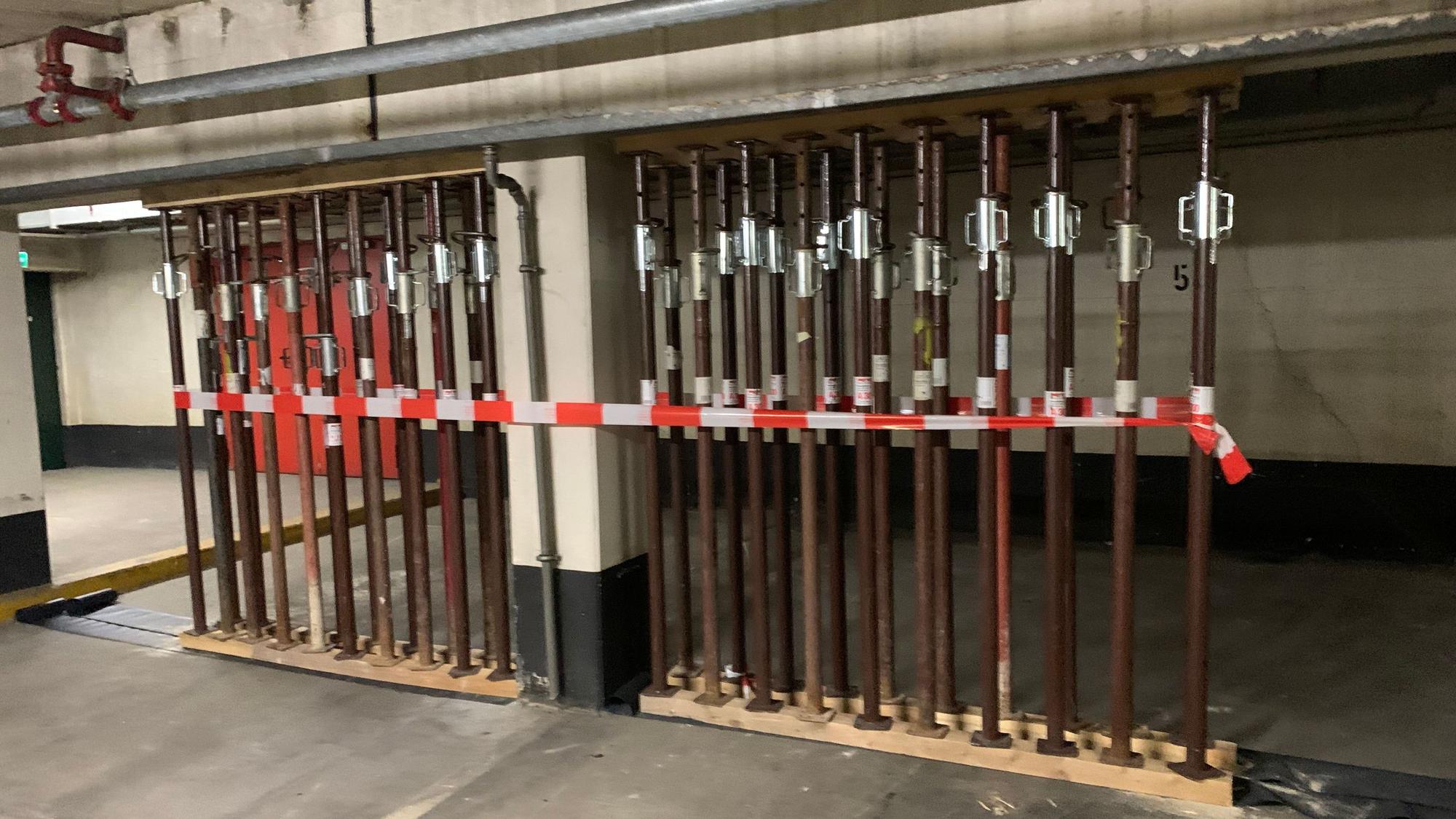 Ein Betonbalken in einer Tiefgarage ist mit Stahlstützen unterbaut.