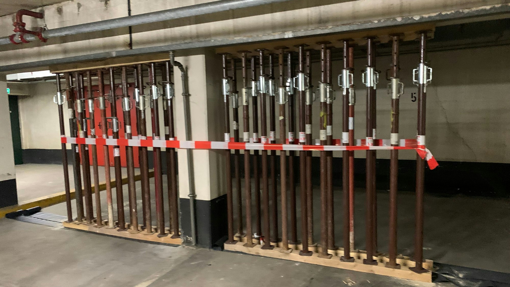 Ein Betonbalken in einer Tiefgarage ist mit Stahlstützen unterbaut.