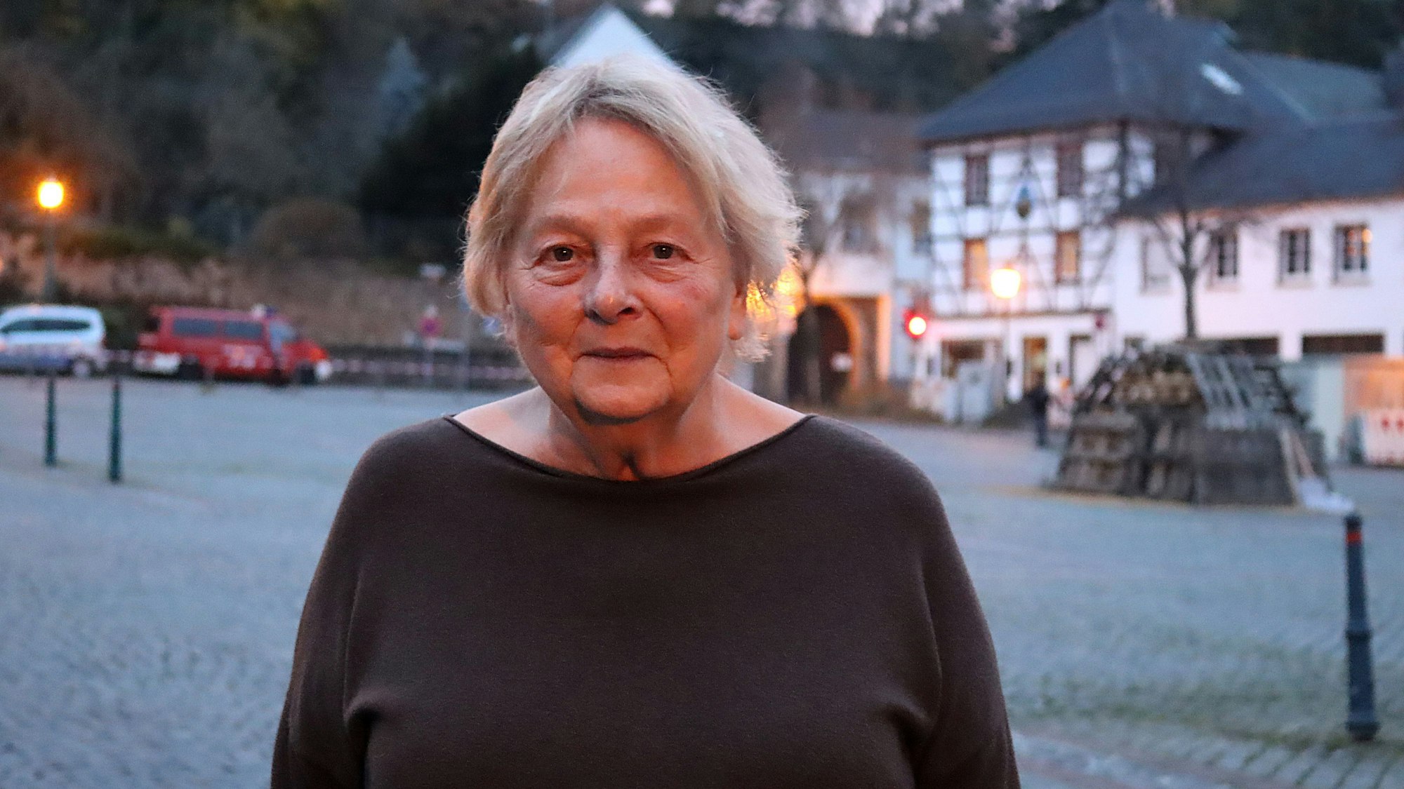 Brigitte Fuchs trägt einen schwarzen Pullover. Im Hintergrund ist ein Fachwerkhaus zu erkennen.