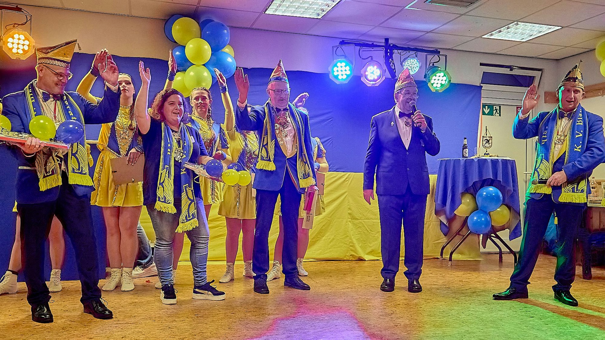 Auf der blau-gelb geschmückten Bühne stehen die Geehrten und Vertreter des KV Blau-Gelb Sieberath und heben die Arme zum Alaaf-Ruf.