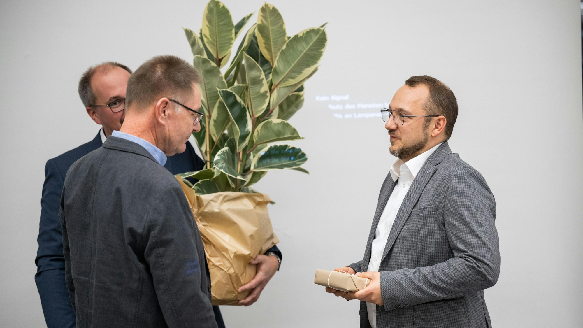 Drei Männer und eine Topfpflanze