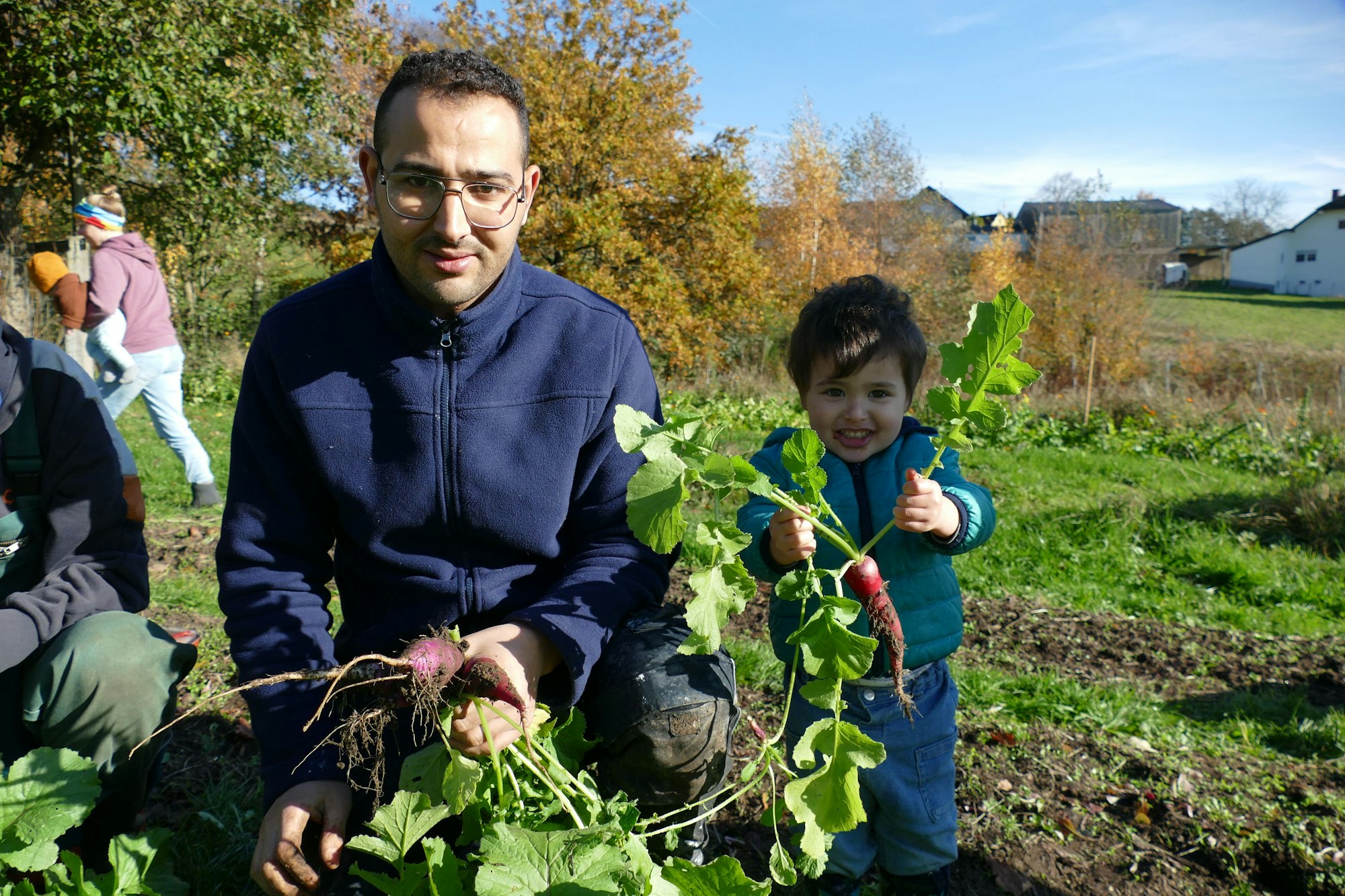 Ein Mann und ein Kind halten Gemüse hoch.