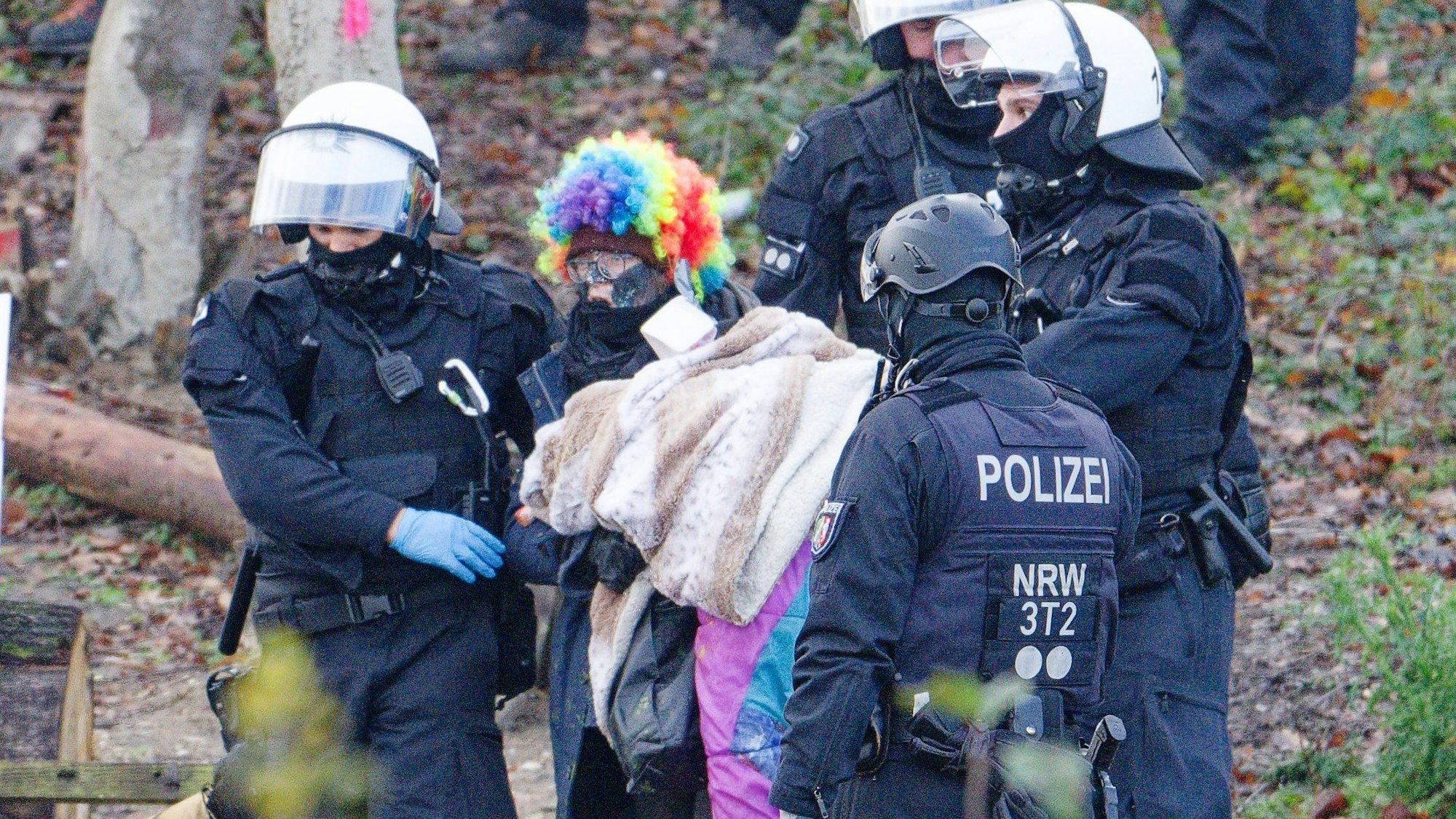 Das Bild zeigt Polizeibeamte, die einen Aktivisten aus dem Wald führen.