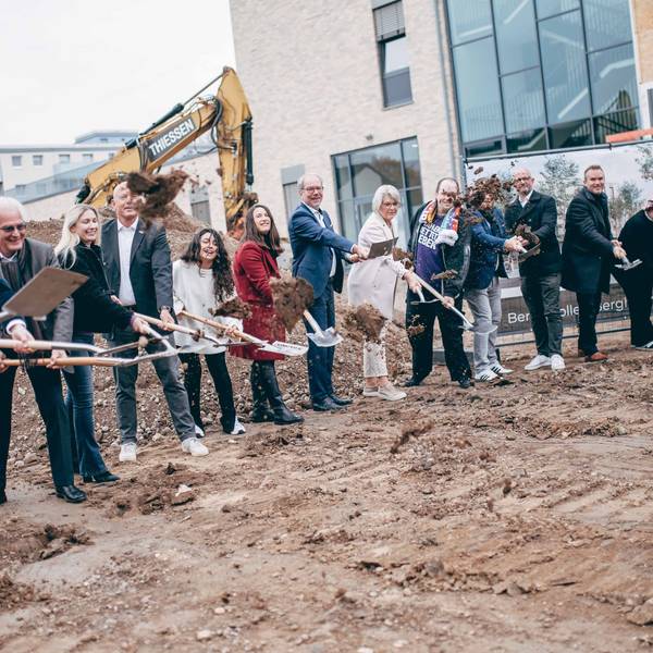 Zu sehen sind zahlreiche Frauen und Männer mit Spaten auf einer Baustelle.