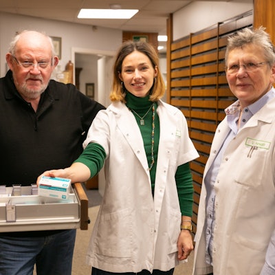 Drei Personen an einem Medikamentenschrank.