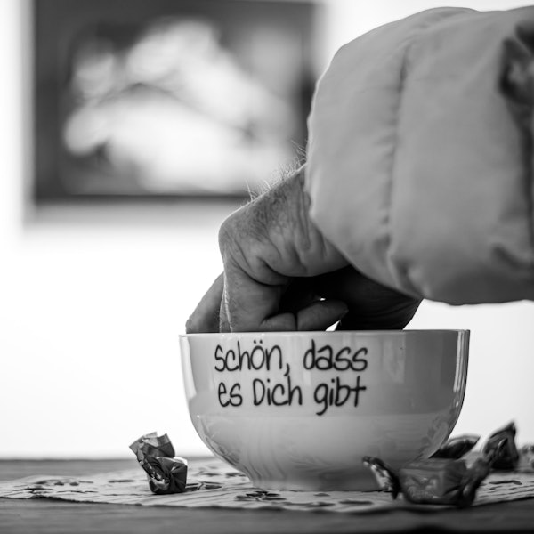 Eine Hand greift in eine Schale mit der Aufschrift „Schön, dass es Dich gibt“.