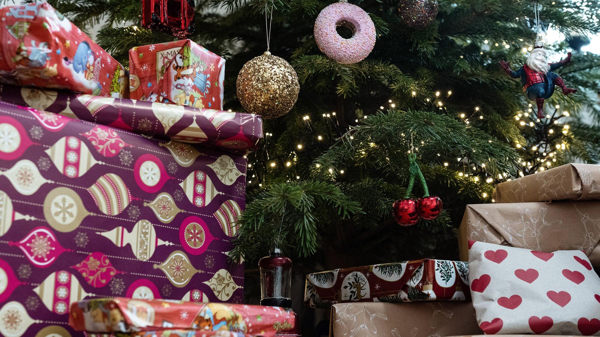 Eingepackte Geschenke liegen unter einem geschmückten Weihnachtsbaum.