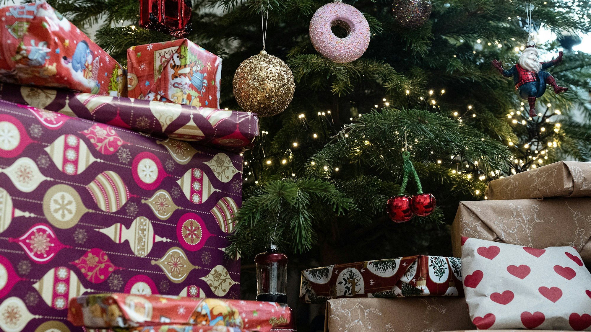 Eingepackte Geschenke liegen unter einem geschmückten Weihnachtsbaum.