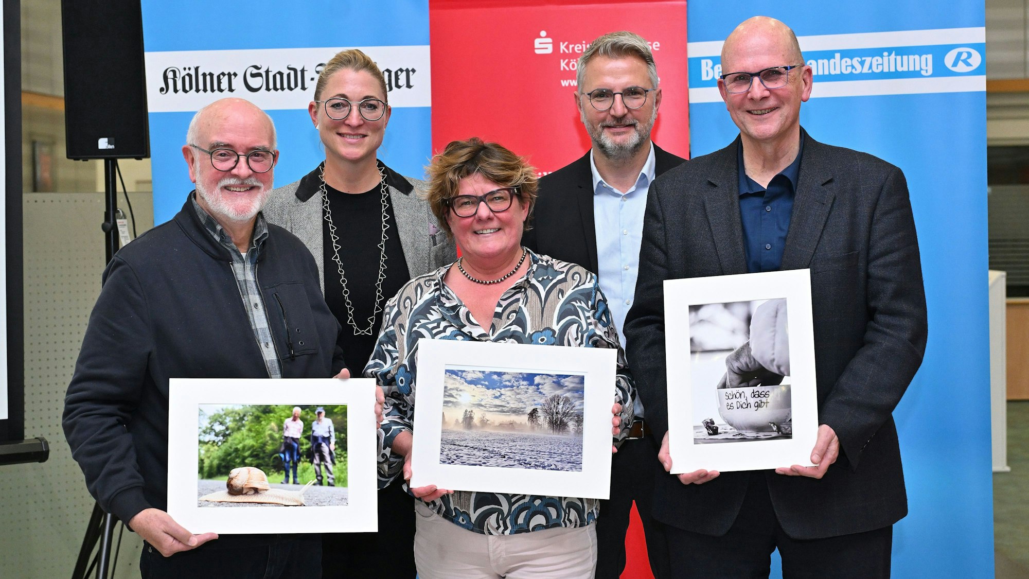 Die Preisträger Wolfgang Müller, Andreas Heine und Frauke Reichel halten ihre Siegerfotos in den Händen.