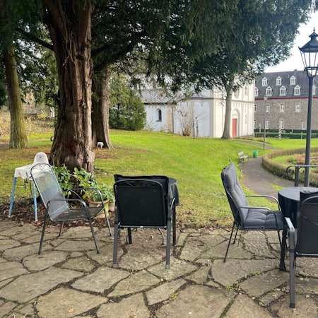 Der Blick von der Terrasse geht in den Schlosspark, auf Springbrunnen, alte Klostergebäude und die Kirche St. Agnes.