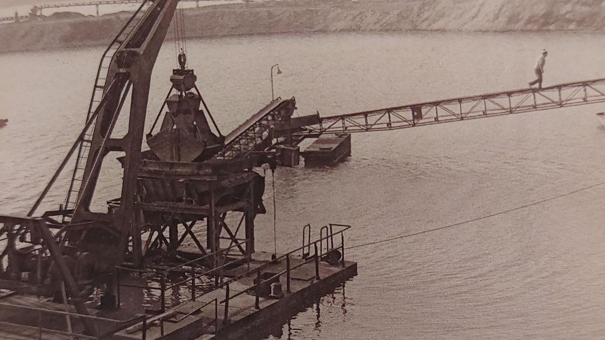 Eine historische Aufnahme eines Schwimmbaggers auf einem See.