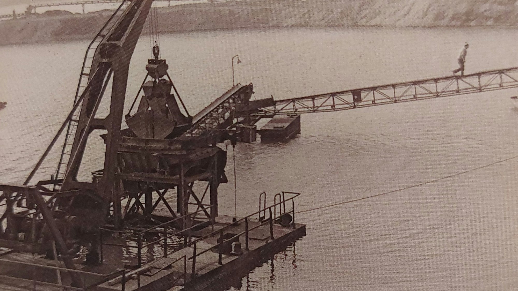 Eine historische Aufnahme eines Schwimmbaggers auf einem See.