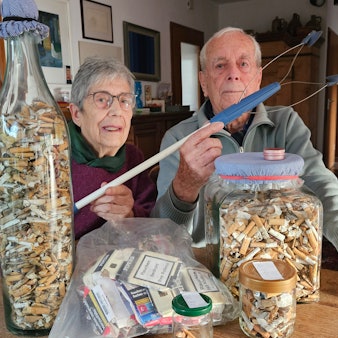 Das Foto zeigt das Ehepaar Margret und Wolfgang Rieve sowie zahlreiche Zigarettenkippen in großen Glasbehältern.