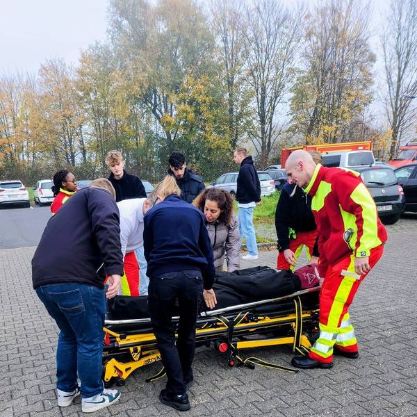 Das Foto zeigt Menschen, die einen Dummy auf einer Liege transportieren.