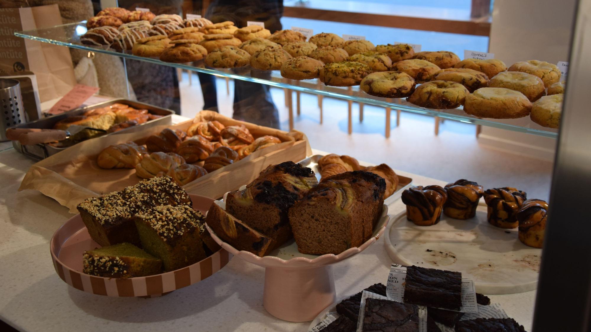 In einer Auslage in einem Café liegen vielfältige süße Leckereien, von Cookies, über Kuchen bis zu Muffins.