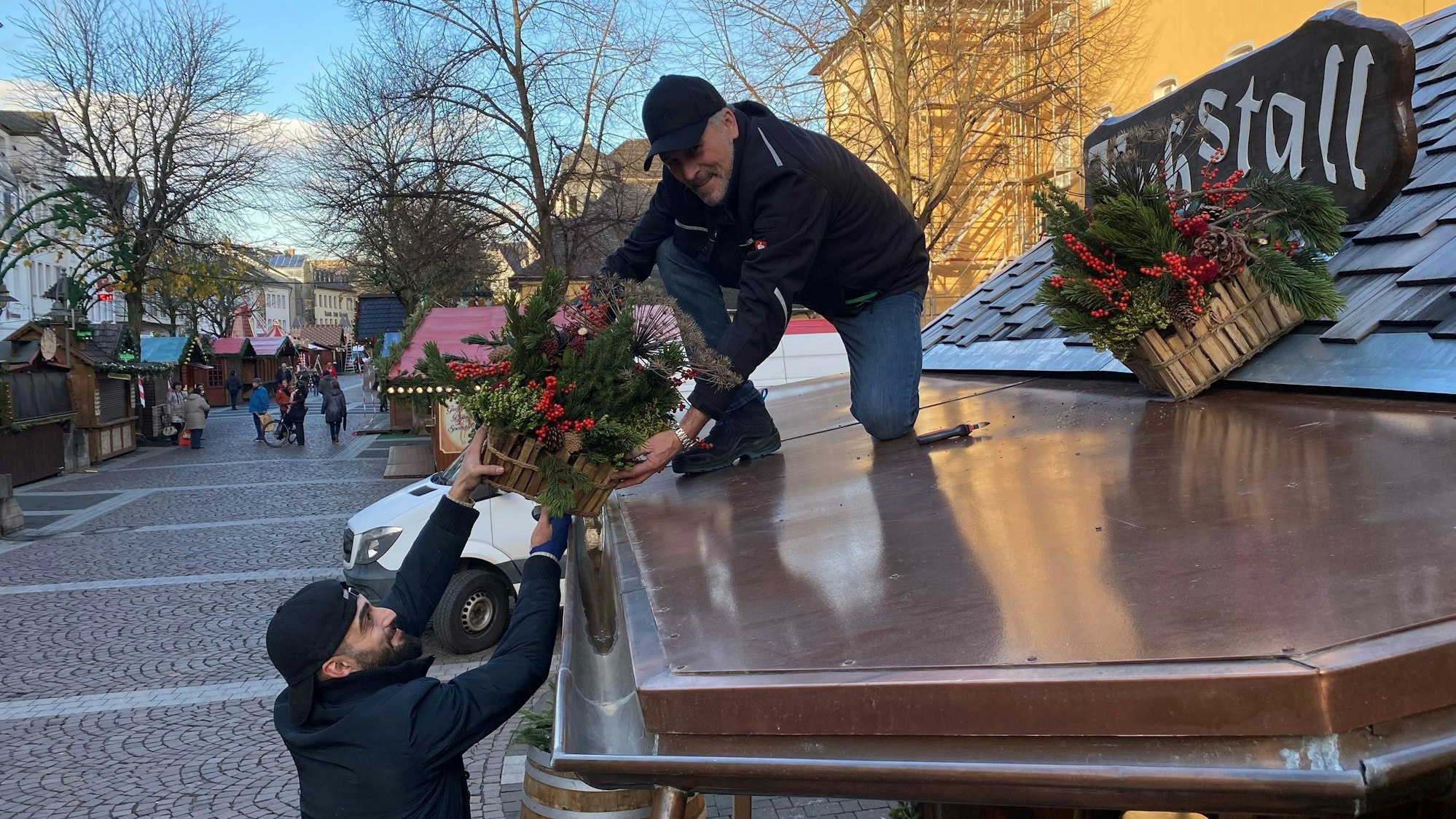 Zu sehen ist, wie ein Mann einem anderen ein Blumengesteck anreicht.