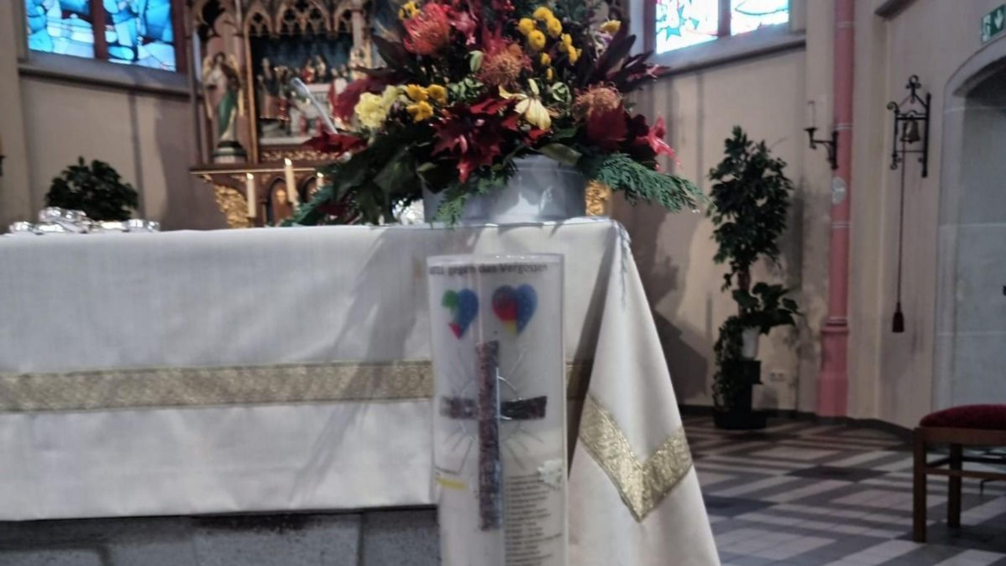 Eine Kerze trägt in der Pfarrkirche in Odendorf die bekannten Namen der Toten aus der Flut 2021 in NRW und RLP
