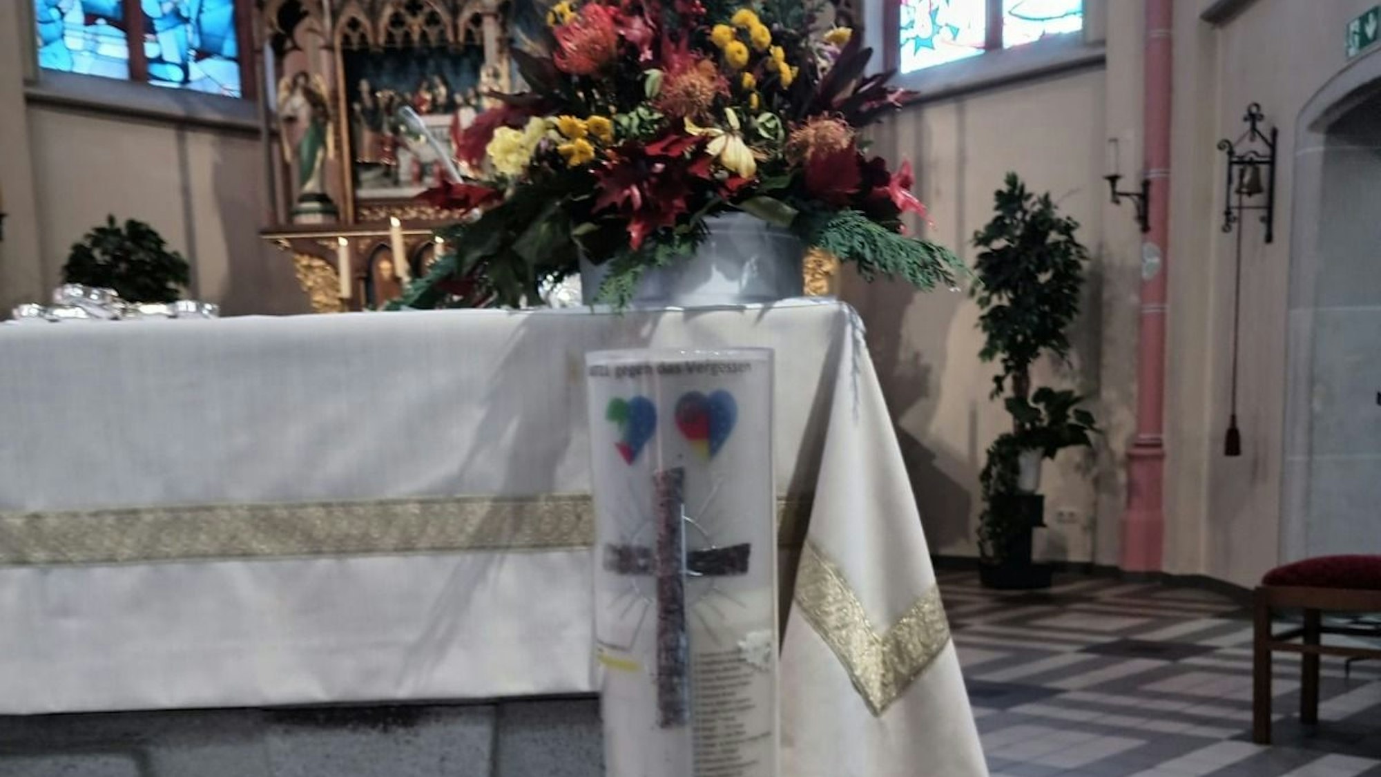 Eine Kerze trägt in der Pfarrkirche in Odendorf die bekannten Namen der Toten aus der Flut 2021 in NRW und RLP