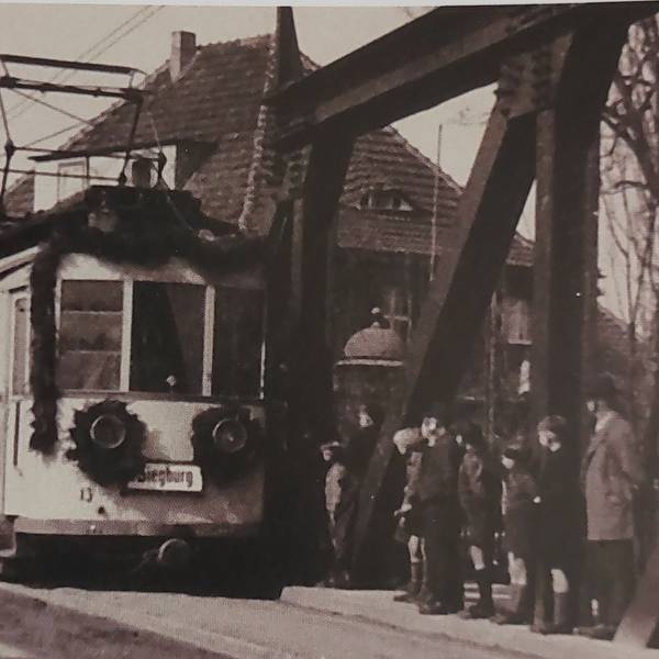 Historische Schwarz-Weiß-Aufnahme einer mit Girlande geschmückten Straßenbahn.