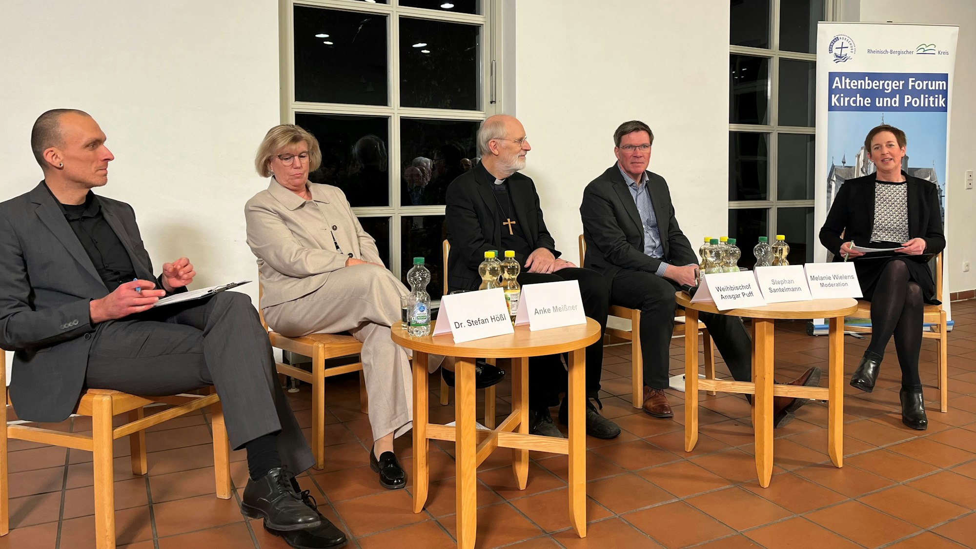 Zwei Frauen und drei Männer sitzen auf einem Podium, dahinter ein Banner mit der Aufschrift„ Altenberger Forum. Kirche und Politik“.