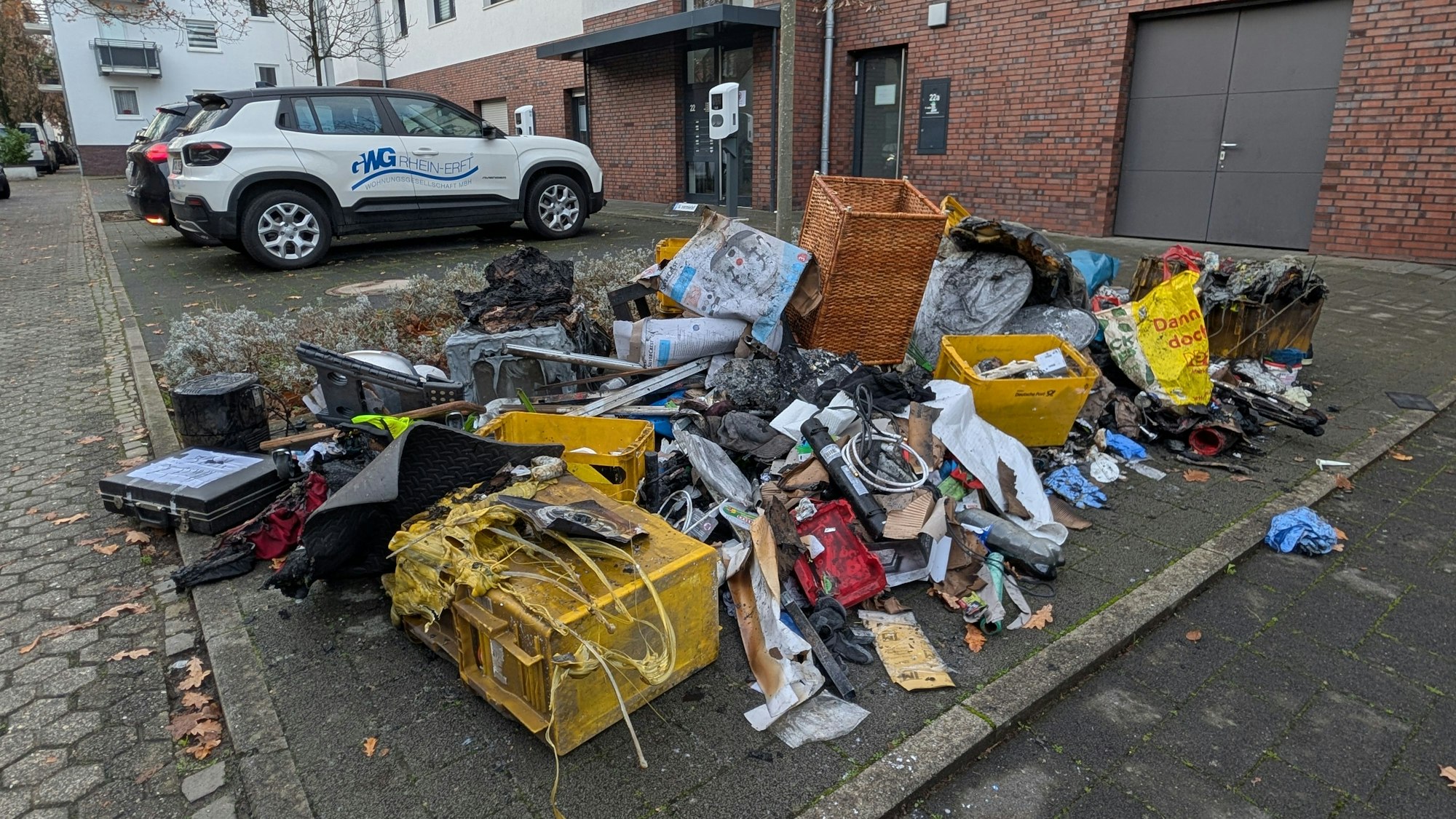Das Foto zeigt verschmortes Material vor dem Mehrfamilienhaus.