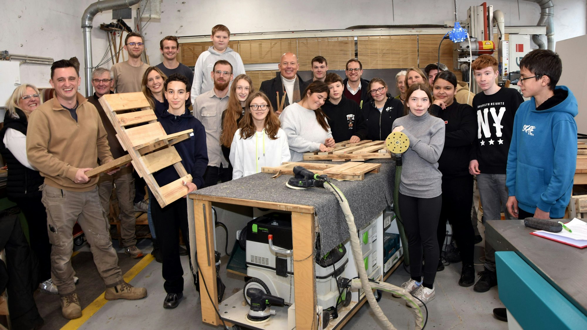 Zu sehen sind zahlreiche Schülerinnen und Schüler in einer Schreinerei.