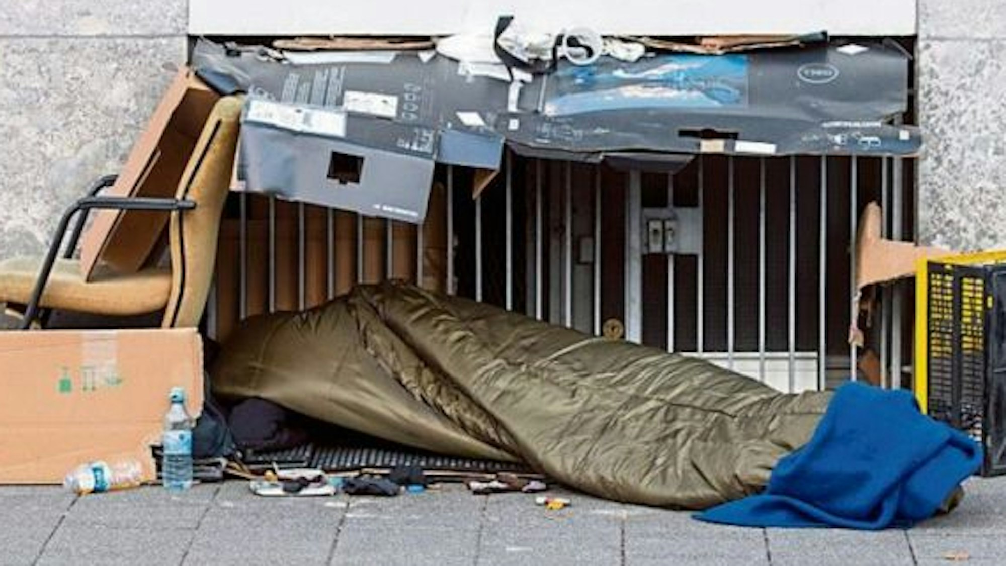 Notdürftig versucht sich dieser Mensch mit Pappe und einem dünnen Schlafsack vor Kälte und Nässe zu schützen.