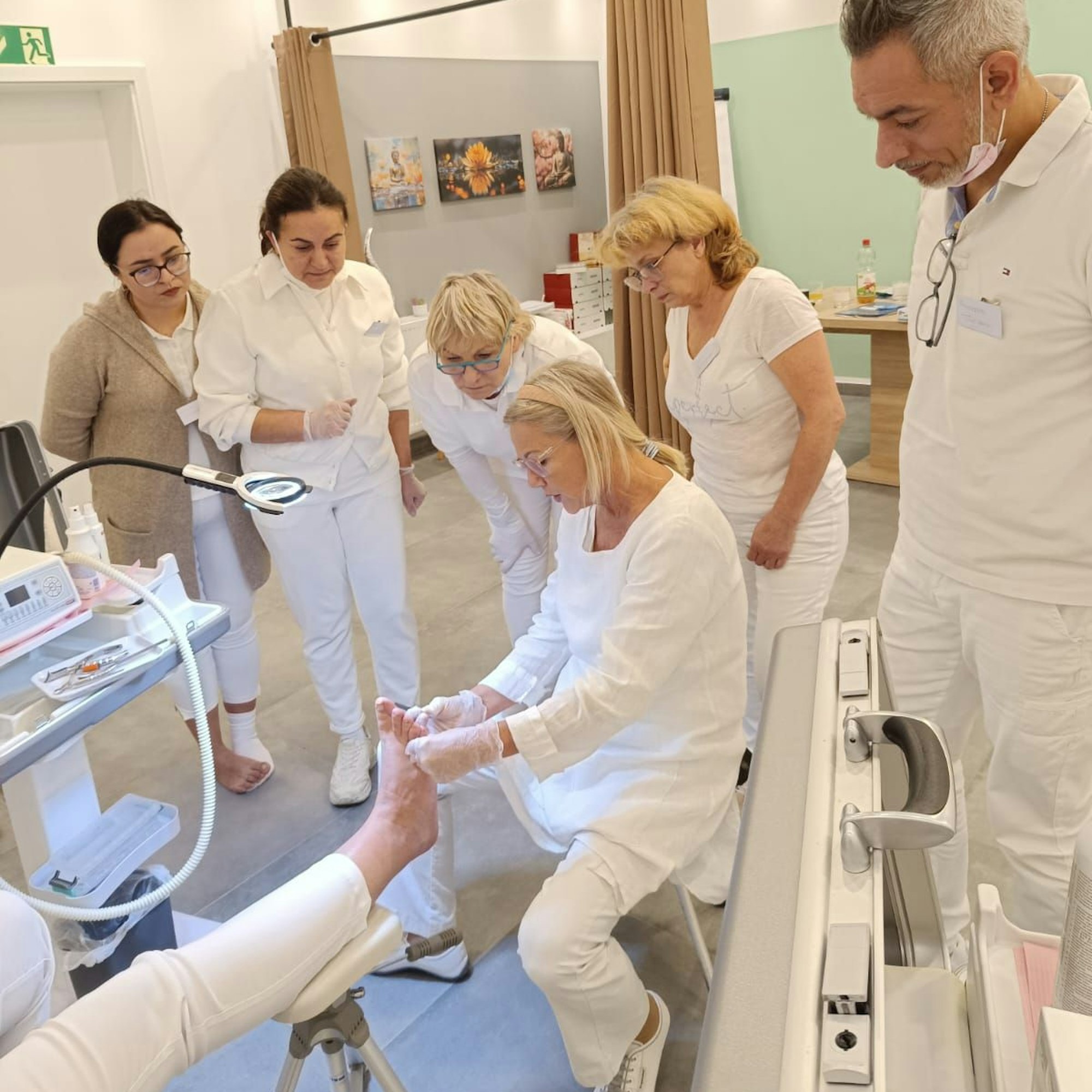 Die Teilnehmer schauen einer Frau bei der Behandlung eines Fußes zu.